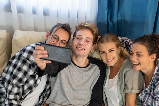 Grupo de jovens fazendo uma selfie, sentado em um sofá