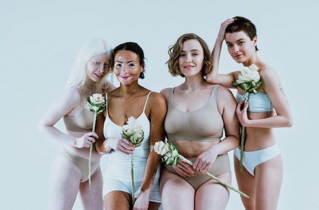 Grupo de mulheres multiétnicas com diferentes tipos de pele posando juntas no estúdio. conceito sobre o corpo