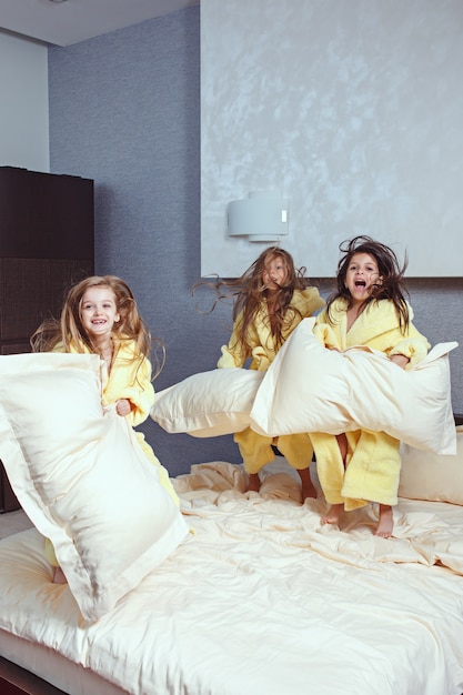 grupo de namoradas se divertindo na cama. Garotas de crianças rindo felizes brincando na cama branca no quarto.