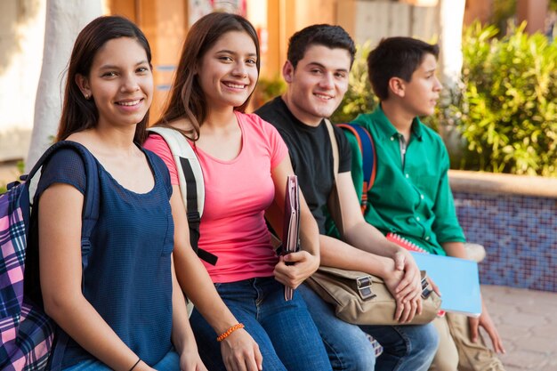 Grupo de quatro amigos adolescentes saindo no ensino médio