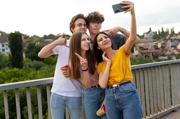 Grupo de quatro amigos passando um tempo juntos ao ar livre e tirando selfie