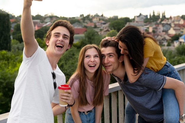 Foto grátis grupo de quatro amigos passando um tempo juntos ao ar livre e tirando selfie