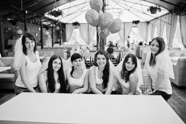 Grupo de seis meninas sentadas à mesa na despedida de solteira com balões Foto gratuita
