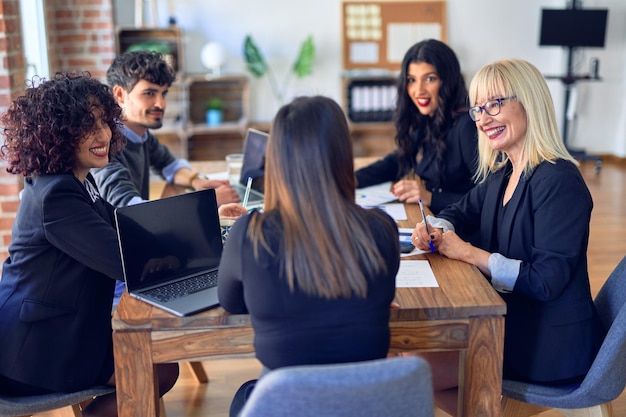 Foto grátis grupo de trabalhadores de negócios sorrindo felizes e confiantes. trabalhando juntos com sorriso no rosto usando laptop e falando no escritório