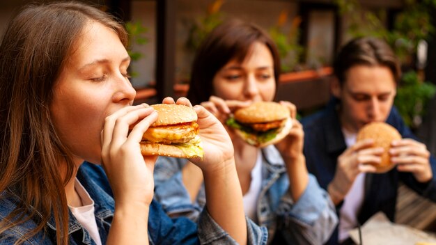 Grupo de três amigos degustando hambúrgueres