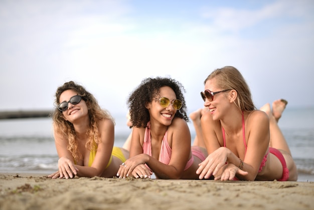 Grupo de três jovens sorridentes na praia - o conceito de felicidade