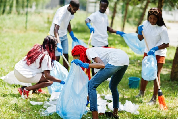 Grupo de voluntários africanos felizes com área de limpeza de sacos de lixo no parque África voluntariando pessoas de caridade e conceito de ecologia