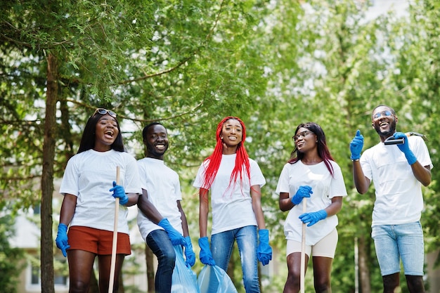 Grupo de voluntários africanos felizes com área de limpeza de sacos de lixo no parque África voluntariando pessoas de caridade e conceito de ecologia