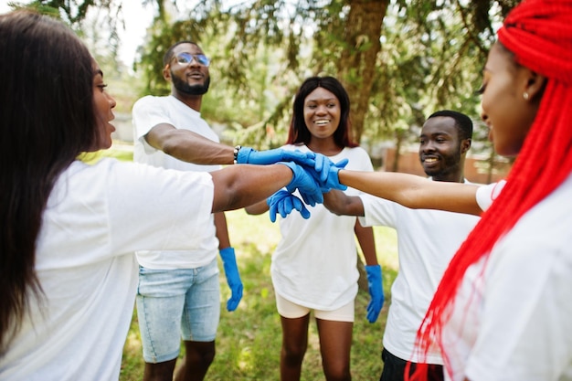 Grupo de voluntários africanos felizes põe as mãos no parque África voluntariando pessoas de caridade e conceito de ecologia
