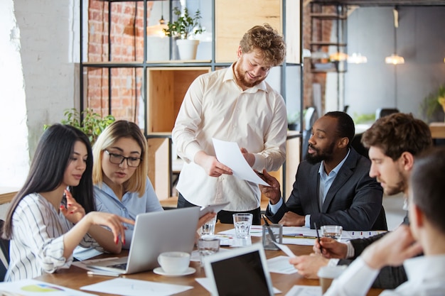 Grupo diversificado de colegas de trabalho tendo uma discussão casual no escritório