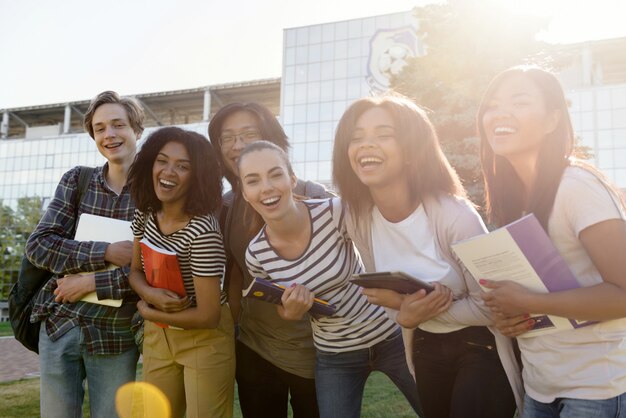 Grupo multiétnico de jovens estudantes alegres em pé ao ar livre