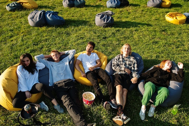 Grupo multiétnico jovem de pessoas assistindo filme no poof no cinema ao ar livre