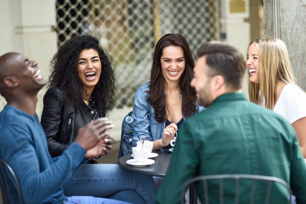 Grupo multirracial de cinco amigos tomando um café juntos