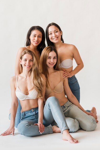 Grupo multirracial de mulheres felizes em sutiãs e jeans