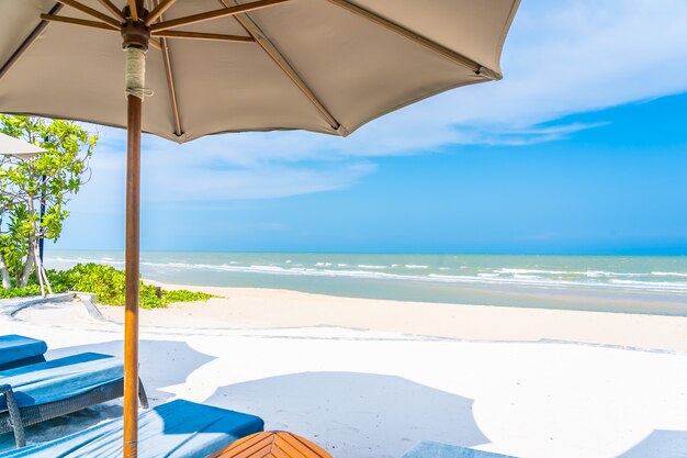 Guarda-chuva e cadeira na praia mar oceano com céu azul e nuvem branca