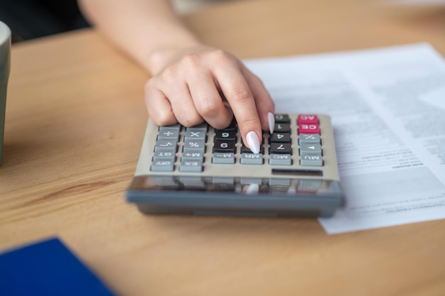 Guarda-livros sentado na mesa do escritório usando uma calculadora de bolso