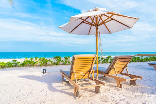 Guarda-sol e espreguiçadeira ao redor da piscina externa em hotel resort com praia e coqueiros