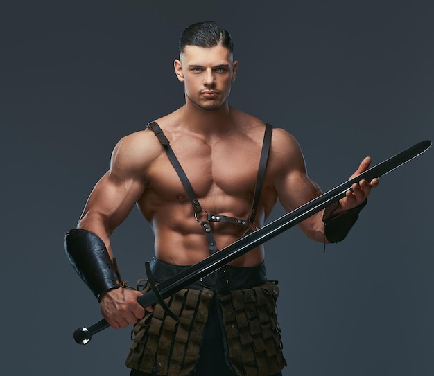Guerreiro brutal da grécia antiga com um corpo musculoso em uniformes de batalha posando em um fundo escuro.