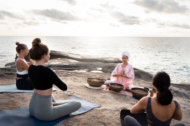 Foto grátis guia de meditação sênior com taças de canto no mar