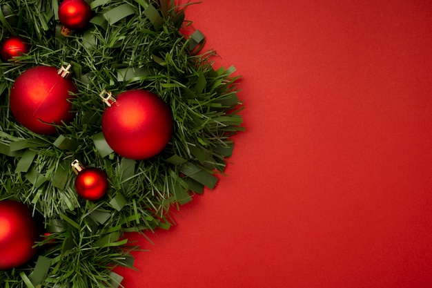 Guirlanda de natal feita de folhas e bolas em uma mesa vermelha | Foto Grátis Guirlanda de natal feita de folhas e bolas em uma mesa vermelha | Foto Grátis