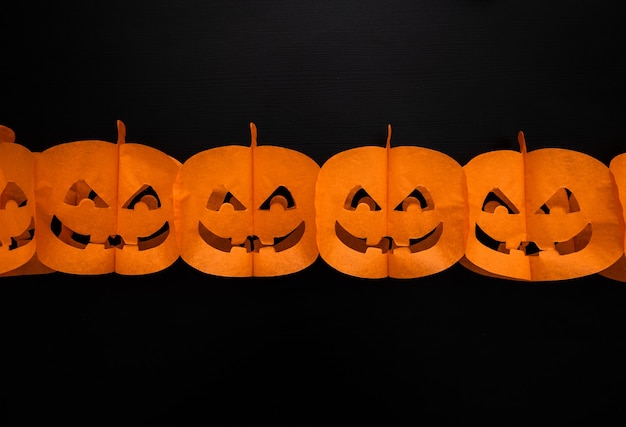 Guirlanda de papel de abóboras de halloween com cara feliz em fundo escuro
