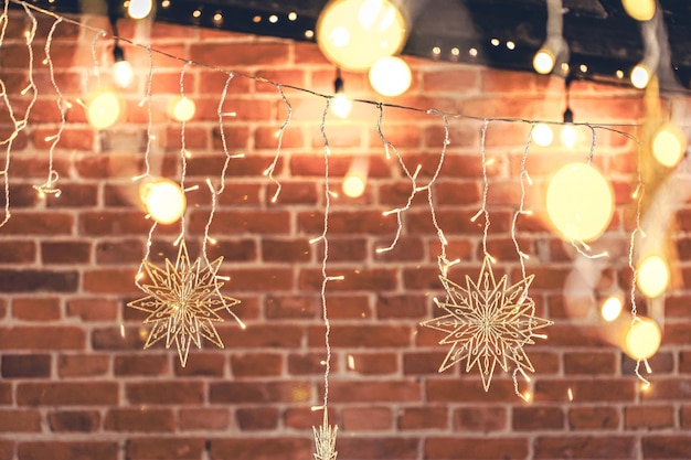 Guirlandas de luzes penduradas na parede de tijolos na decoração da casa de natal à noite