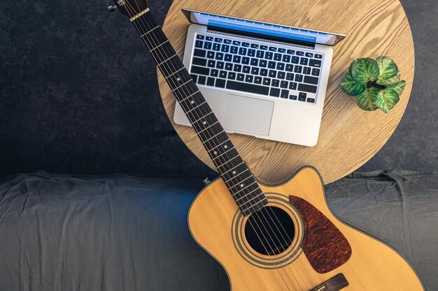 Guitarra acústica e laptop em uma mesa de madeira