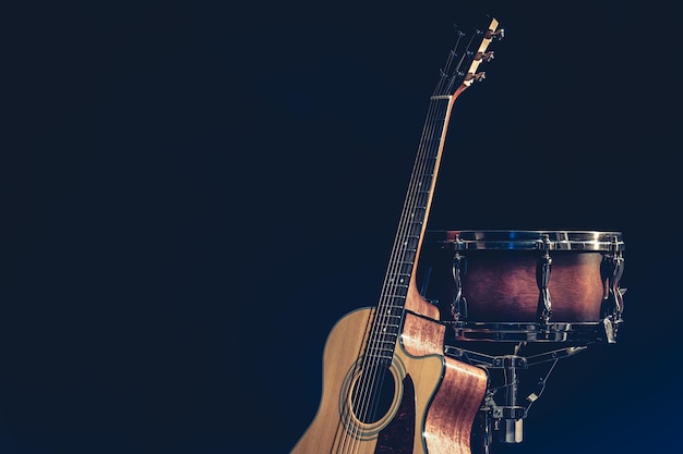 Guitarra acústica e tarola em um fundo preto isolado