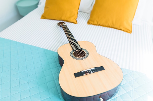 Guitarra de madeira na cama no quarto
