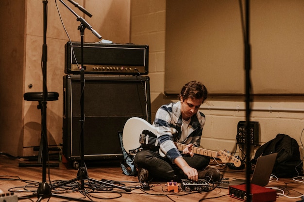 Guitarrista gravando rock em estúdio, sentado no chão