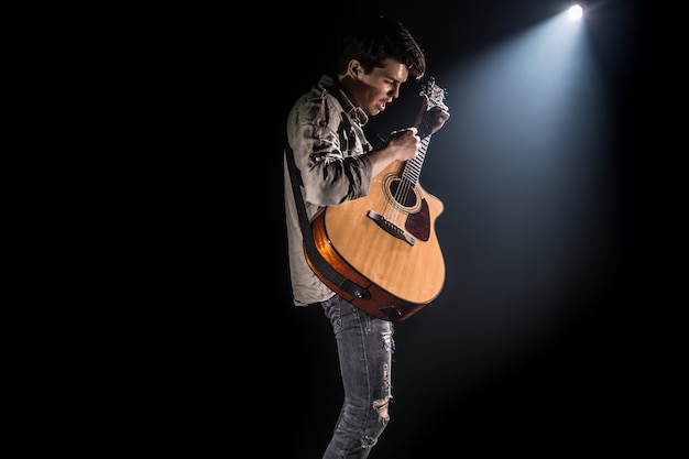 Guitarrista, música. um jovem toca violão em um fundo preto isolado. luz pontiaguda