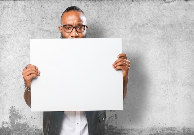 Foto grátis guy segurando um cartaz em branco com fundo da parede