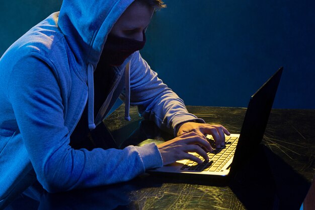 Hacker de computador com capuz, roubar informações com o laptop