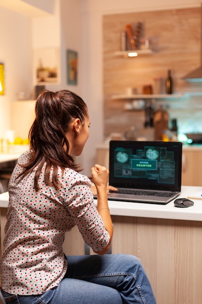 Foto grátis hacker de mulher feliz depois de quebrar o firewall do governo e obter acesso concedido. programador que cria um malware perigoso para ataques cibernéticos usando laptop de alto desempenho durante a meia-noite.