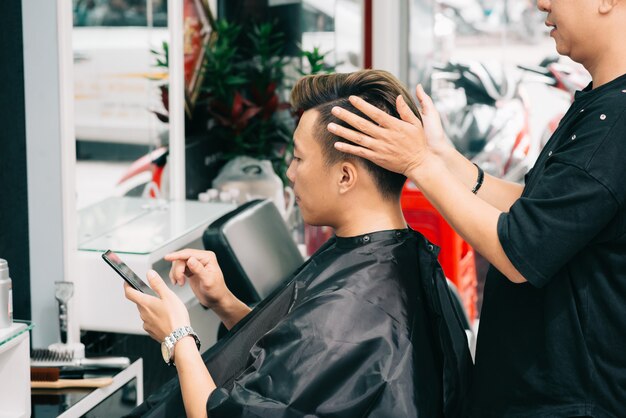 Hairstylist cortado que dá o toque final ao hairdo do cliente masculino