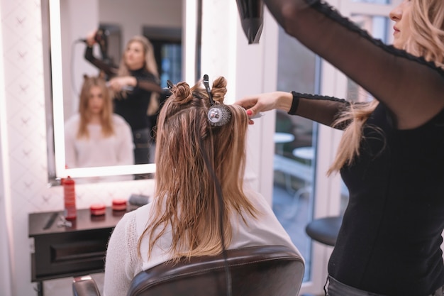 Foto grátis hairstylist profissional que ajusta o cabelo do cliente