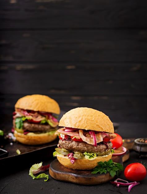 hambúrguer com carne, tomate, pepino em conserva e bacon frito.