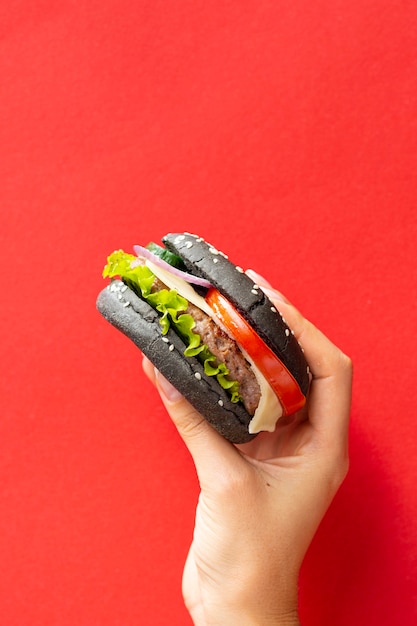 Hamburguer com pão preto sobre fundo vermelho