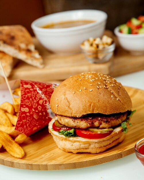 Hambúrguer de carne com batatas fritas em uma placa de madeira