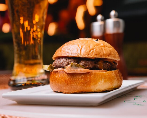 Hambúrguer de carne com molho de pepino em conserva servido no restaurante com cerveja