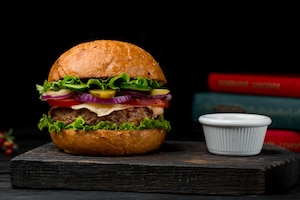 Foto grátis hambúrguer de carne cotlet com molho em uma placa de madeira