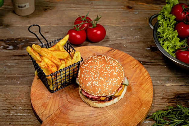 Hambúrguer grande e batatas fritas servidas em uma tábua de madeira em um café