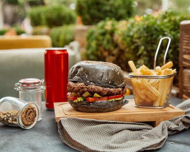 Hambúrguer preto com batatas fritas e cola