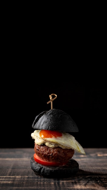 Foto grátis hambúrguer preto de vista frontal com ovo e cópia-espaço