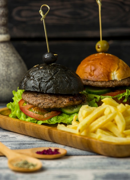 Foto grátis hambúrguer preto e branco com batatas fritas em bandeja de madeira