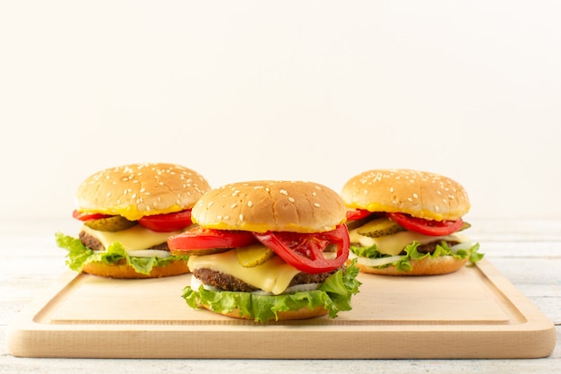 Hambúrgueres de frango com queijo e salada verde na mesa de madeira e sanduíches fast-food