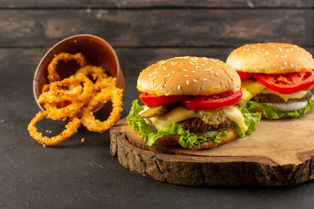 Hambúrgueres de frango com salada de queijo verde e anéis de cebola na mesa de madeira e sanduíches fast-food