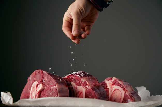 Foto grátis hand está preparando três bifes de carne fresca com osso