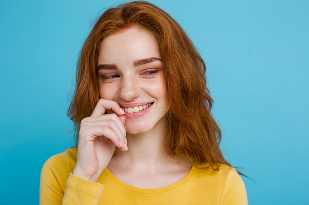 Headshot retrato de feliz gengibre menina de cabelo vermelho com sardas sorrindo olhando câmera. fundo azul pastel. espaço de cópia.