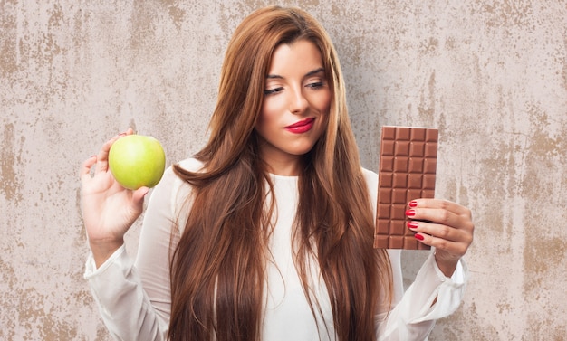 Foto grátis hesitando mulher com maçã e chocolate